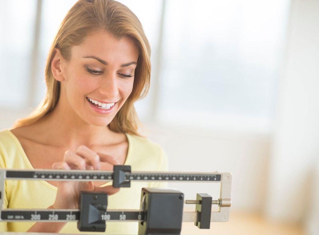 woman weighing herself to see her weight loss results on tirzepatide o'fallon illinois